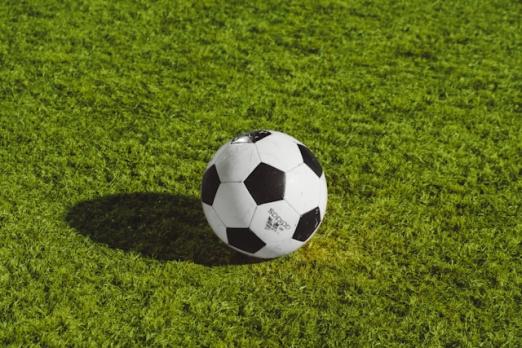 Soccer ball on green grass under sunlight.